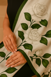 A woman sitting and posing with a green and white silk dupatta with a floral pattern draped over her shoulders.